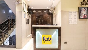 A reception desk with a 'fab hotels' sign, a staircase, and a wall with a menu board. - Fabhotel Starlight Nx (Chhatrapati Sambhajinagar)