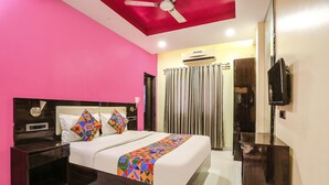 A hotel room with a bed, a nightstand, a TV, and an air conditioning unit. - Fabhotel Starlight Nx (Chhatrapati Sambhajinagar)