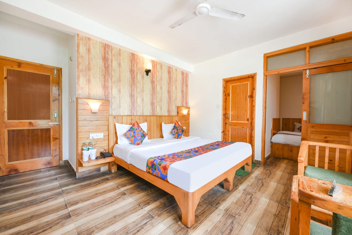 A wooden-framed bed with a colorful blanket, a nightstand with a lamp, and a wooden door with a frosted glass panel.