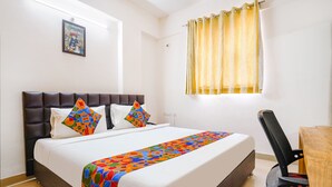 A neatly made bed with a colorful bedspread, a headboard, and two pillows. - FabHotel Blue Dawn Suites (Hyderabad)