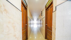 A long, narrow hallway with marble walls and wooden doors. - Fabhotel Bns Lodge (Bengaluru)