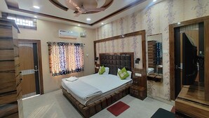 A bedroom with a large bed, a ceiling fan, and a window with curtains. - Fabhotel Cm Palace I (Varanasi)