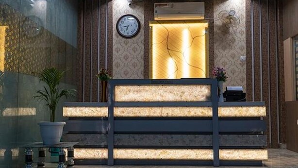 A reception desk with a clock, a plant, and a vase of flowers. - Fabhotel Cm Palace I (Varanasi)