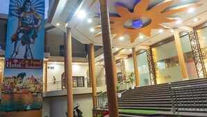A hotel interior with a large sun-like ceiling design, a mural of a deity, and a staircase leading to an upper level. - Fabhotel Cm Palace I (Varanasi)