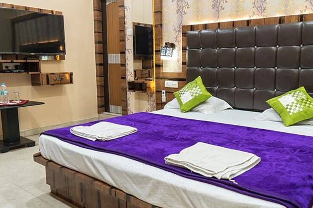 A hotel room with a large bed, a flat-screen TV, and a small table with a water bottle.
