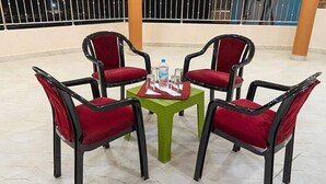 A four-chair table with red cushioned chairs and a green tablecloth, set on a tiled floor. - Fabhotel Cm Palace I (Varanasi)