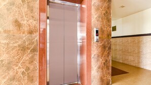 An elevator in a lobby with marble walls and a digital display. - Fabhotel Sanjay Palace (Jaipur)