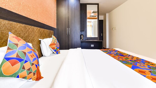 A hotel room with a bed, pillows, a wardrobe, and a mirror. - Fabhotel Sanjay Palace (Jaipur)