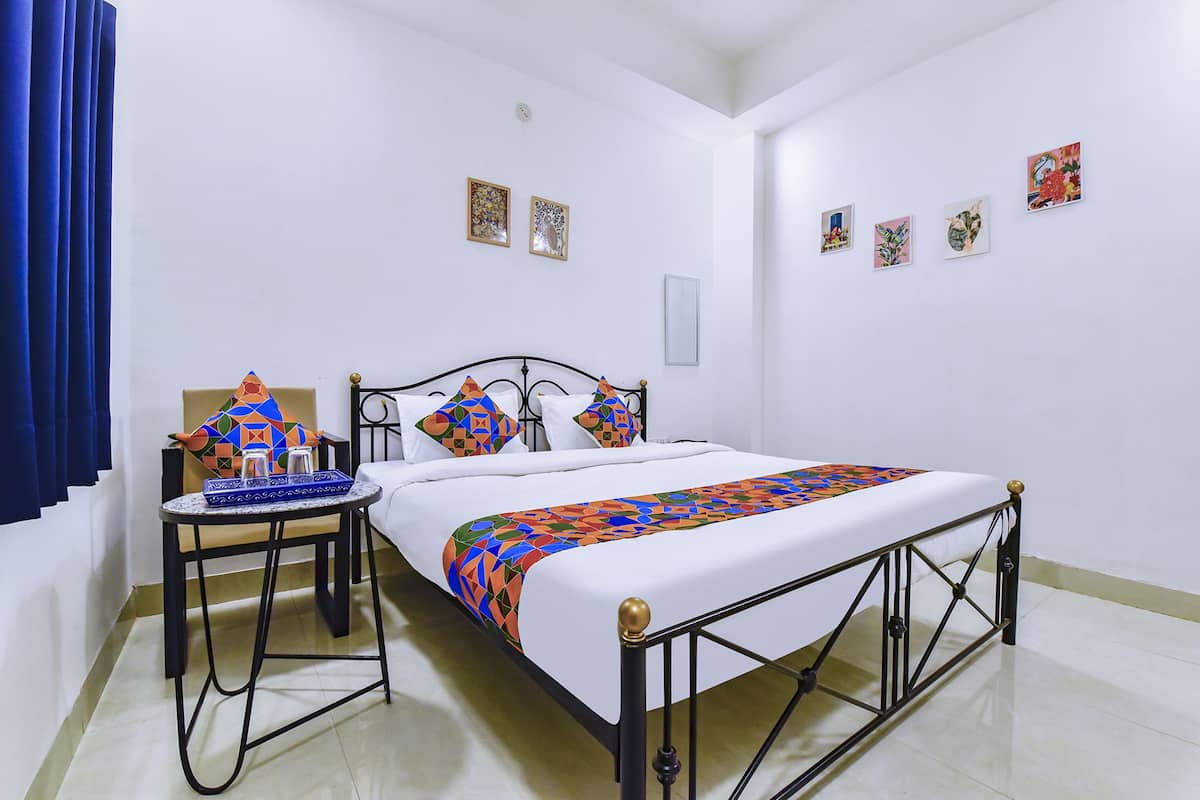 Un dormitorio ordenado con cama, una mesita y un adorno, además de una silla.