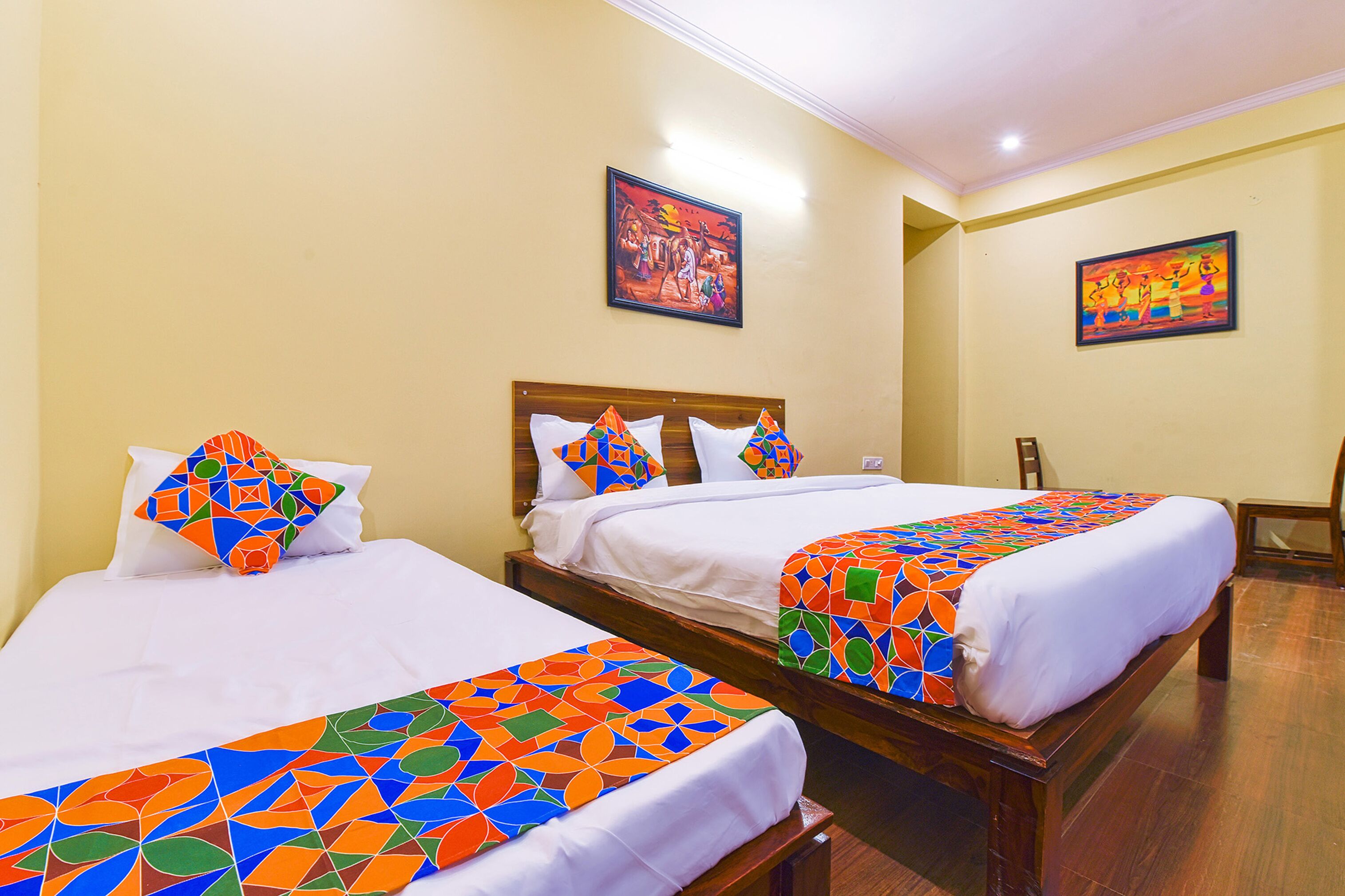 Two beds with colorful geometric-patterned bedspreads, wooden headboards, and white pillows.