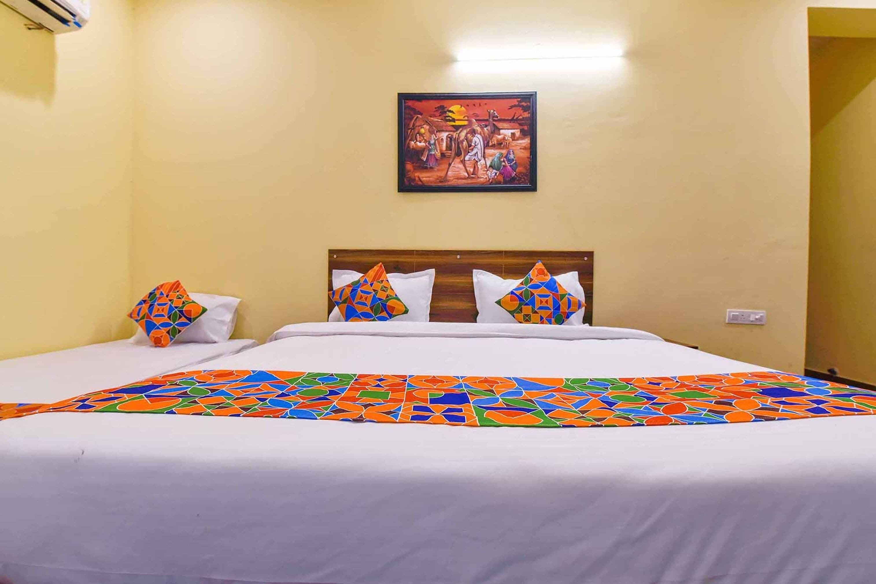 Una habitación de hotel con una cama, un cuadro en la pared y una colcha de colores.