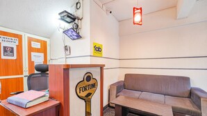 A hotel reception area with a wooden desk, a couch, and a key-shaped sign labeled "FORTUNE". - Fabhotel Emirates Inn (Bengaluru)