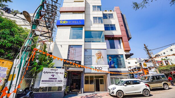 A multi-story building with a 'fab hotels' sign, a 'Fortune Ke' sign, and a 'KID' sign. - Fabhotel Emirates Inn (Bengaluru)