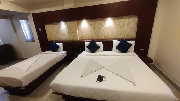 Habitación de hotel con dos camas, cabecero con cortinas y un control remoto sobre la cama.