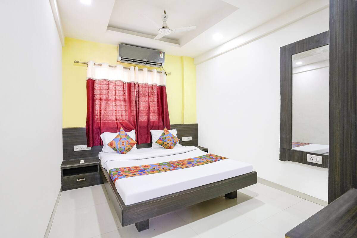 A bedroom with a bed, a nightstand, a bedside table, a mirror, and a ceiling fan.