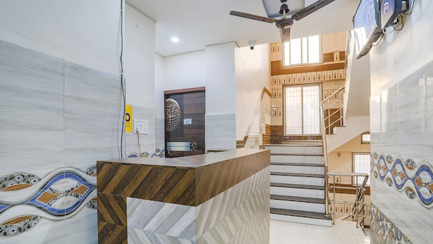 A modern interior with a reception desk, a staircase, and a ceiling fan. - Fabexpress Convivial Star (Raipur)