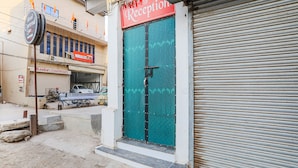 A hotel reception with a closed shutter, a signboard for 'Hotel Carnival', and a parked bicycle. - Fabexpress Convivial Star (Raipur)