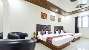 Ein Hotelzimmer mit einem großen Bett, einem Sessel und Kunstwerken an den Wänden.