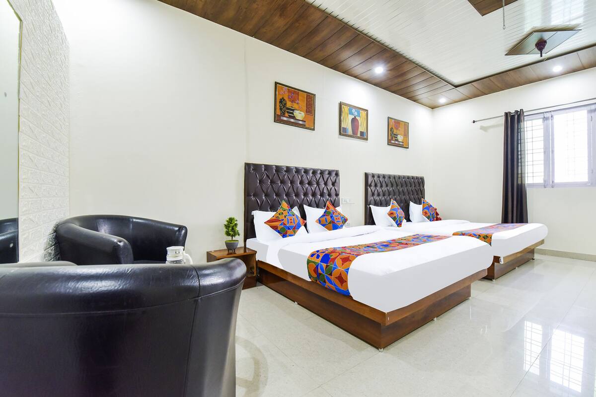 A hotel room with a large bed, a chair, and artwork on the walls.