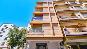 Un hotel de diverses plantes amb balcons, un senyal amb 'Tab Hotels' i un arbre al davant.