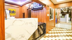 A hotel reception area with a marble counter, wooden paneling, a television, and a glass door leading outside. - Fabhotel Prime Diamond Palace (Bhopal)