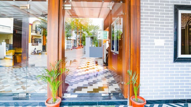 A hotel entrance with a checkered floor, wooden pillars, and potted plants. - Fabhotel Prime Diamond Palace (Bhopal)