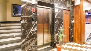 An elevator with a marble wall, a reception area, and a staircase. - Fabhotel Prime Diamond Palace (Bhopal)