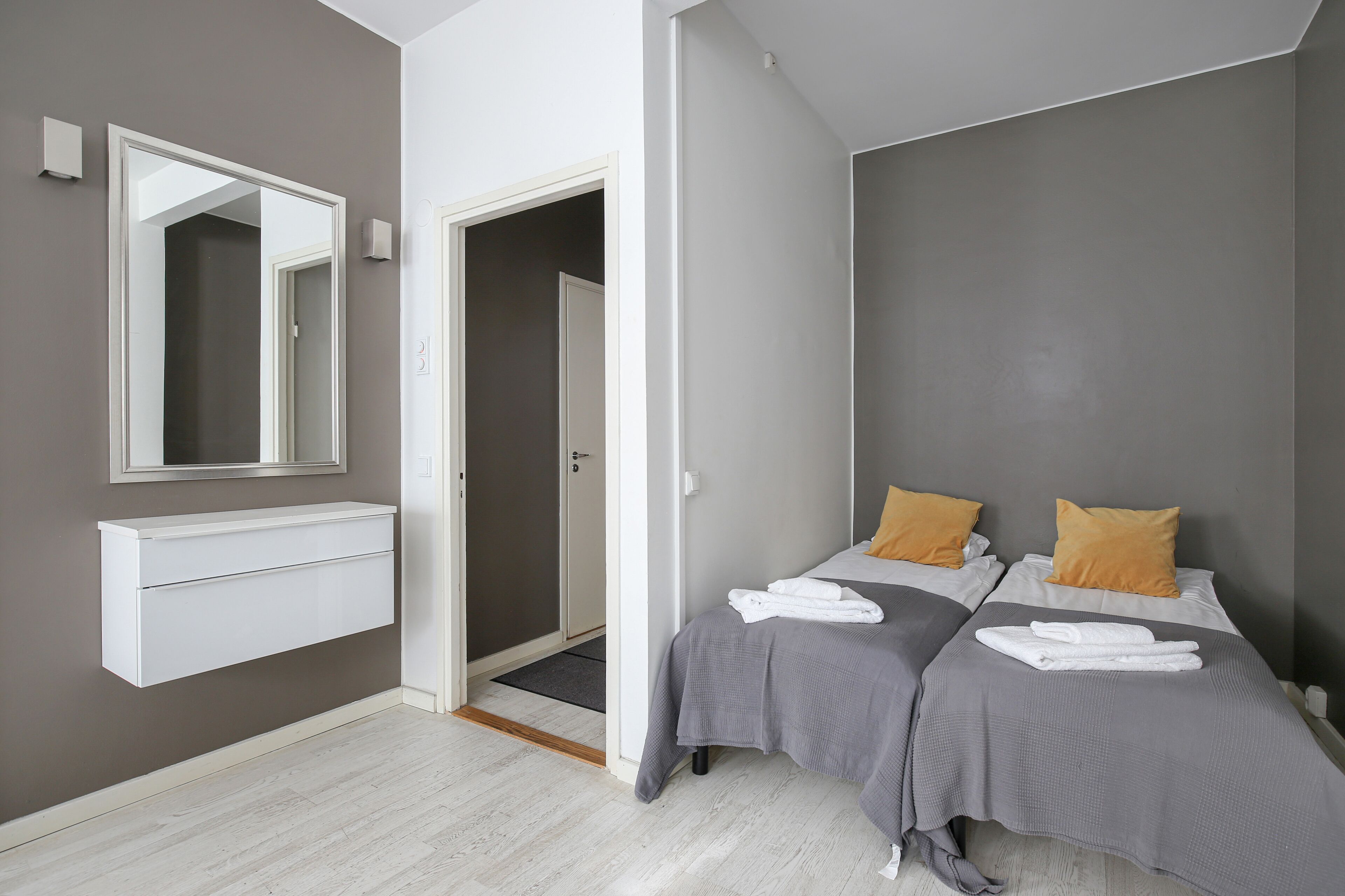Een moderne slaapkamer met twee bedden, een inbouwkast en een grote spiegel.