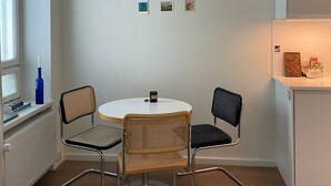 A modern, minimalist dining area with a round table, two chairs, and a pendant light. - Kotimaailma Aparthotel Kamppi - Studios (Helsinki)