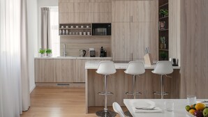 A modern kitchen with wooden cabinetry, a central island with bar stools, and a dining area with a white table set.