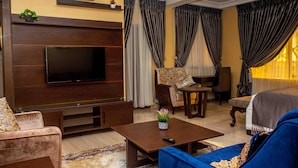 Una sala de estar moderna con un televisor de pantalla plana, un sofá, una mesa de centro y un comedor.