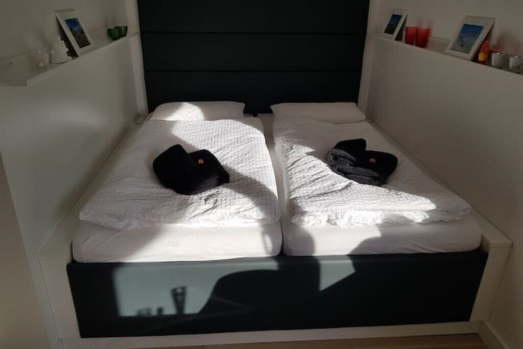 A small, private room with two beds, each with white linens and black slippers.