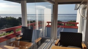 A balcony with a view of the sea, wooden furniture, and a glass partition. - Little Skysuite W 94 (Cuxhaven)