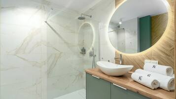 Een moderne badkamer met een grote ovale spiegel, een wastafel en een douchecabine.