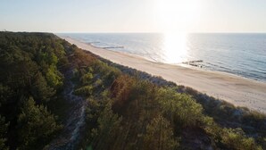 Une plage bordée d’une zone boisée et d’une jetée qui s’avance dans l’eau.