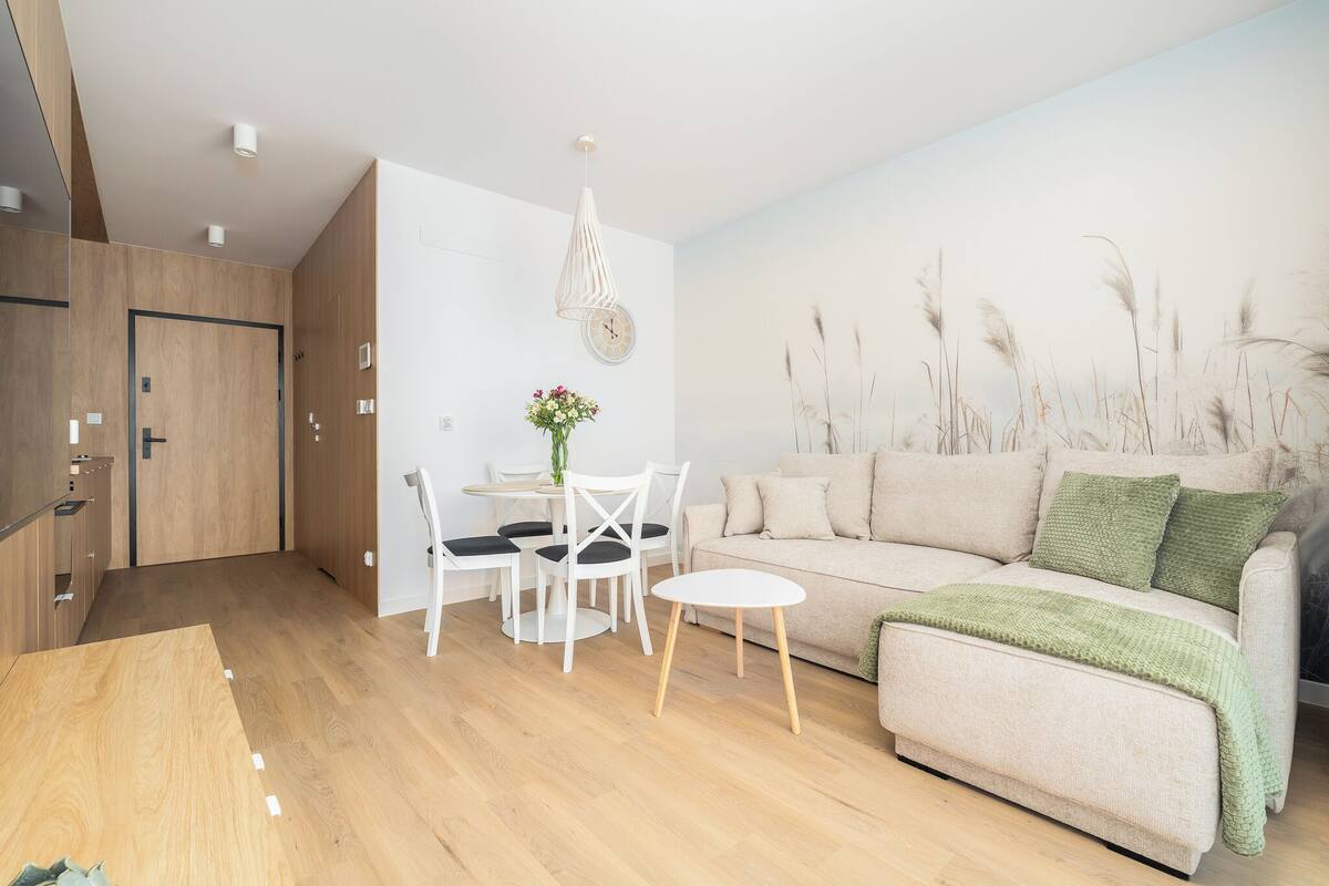 Una sala de estar moderna con un sofá, una mesa de comedor con sillas y una pequeña mesa blanca.
