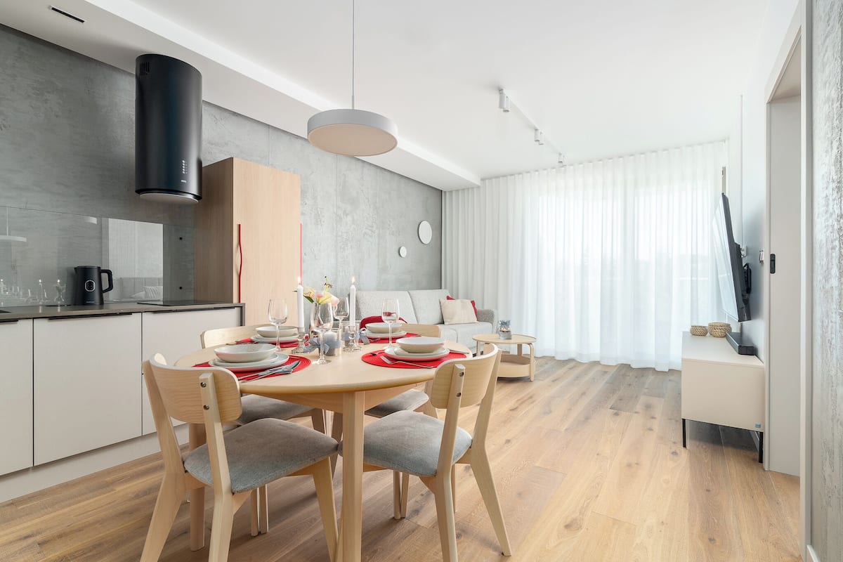 Una cocina moderna con comedor, sillas de madera y una mesa lista para una comida.