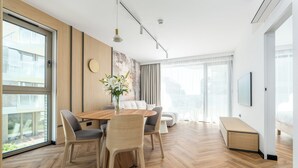 Un salon moderne avec une table à manger en bois, des canapés gris et une grande fenêtre.