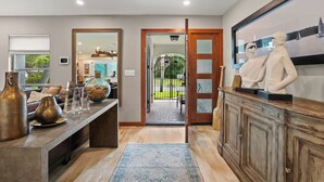 A modern interior with a wooden cabinet, a large mirror, and a sculpture on the wall. - Rustic Sands - 650   “Siesta Key” (Sarasota)