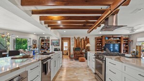 A spacious kitchen with modern appliances, wooden beams, and a central island. - Rustic Sands - 650   “Siesta Key” (Sarasota)