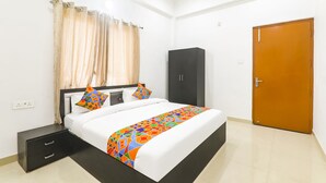 Una camera d'albergo con un letto, un armadio, un comodino e una porta.