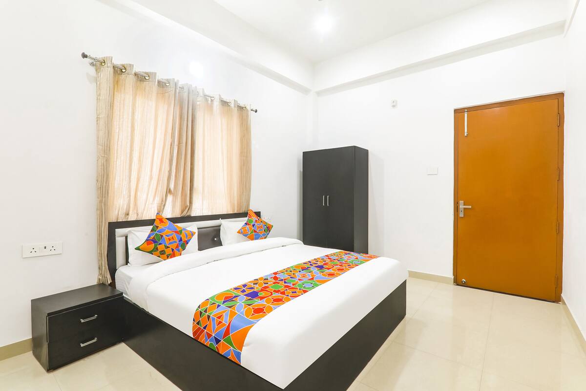 Quarto de hotel com cama, guarda-roupa, mesa de cabeceira e porta.