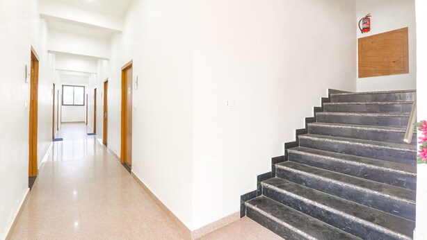 Un corridoio pulito e ben illuminato con pavimento in marmo che conduce a una scala con gradini scuri.