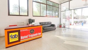 Un'area di accoglienza con reception, un divano in pelle, ampie finestre e una ventola a soffitto.