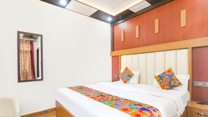 Una habitación de hotel con una cama grande, un cabecero de madera, una mesita de noche y una silla.