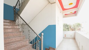Una escalera con barandillas de metal y escalones de granito que lleva a un balcón con un muro blanco y azul.