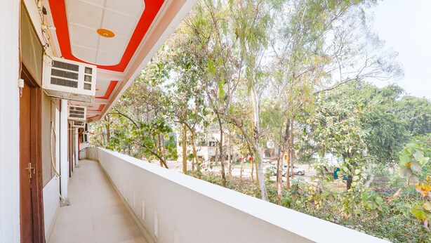 Un pasillo con techo blanco, unidades de aire acondicionado y vistas a árboles y una carretera.