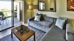 A living room with a grey sofa, two patterned pillows, a wooden coffee table, and a floor lamp. - Ellefsen Golf Suite 106 Langebaan 4-slpr (Langebaan)
