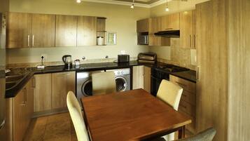 A compact kitchen with wooden cabinets, a built-in washing machine, a microwave, and a toaster.