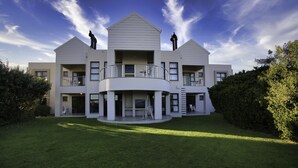 A modern multi-story building with a central courtyard, balconies, and a well-maintained lawn. - Ellefsen Golf Suite 106 Langebaan 4-slpr (Langebaan)